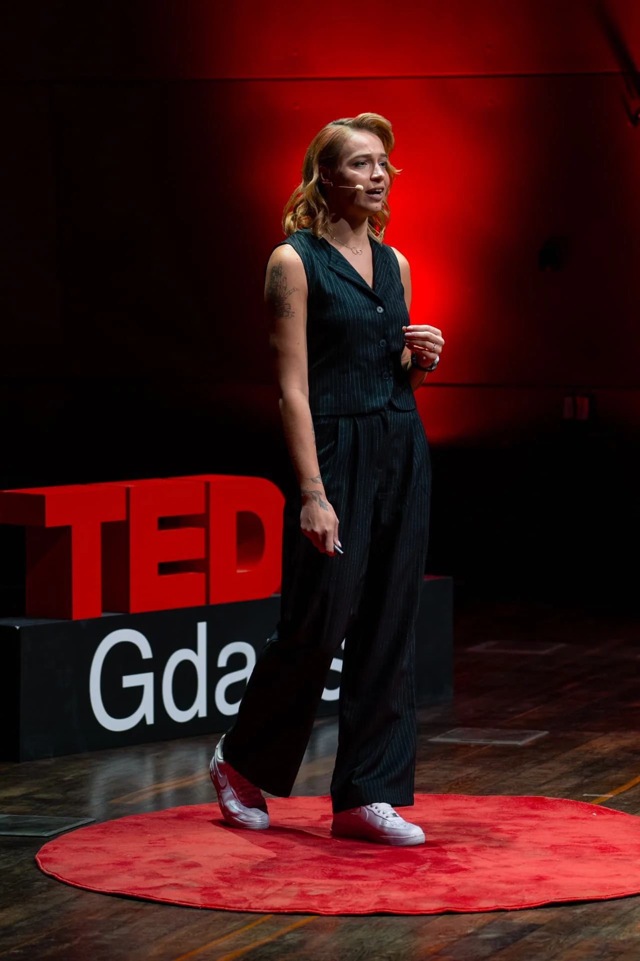 Kama Kotowska na scenie TEDx Gdańsk, na czerwonym dywanie, podczas wystąpienia
