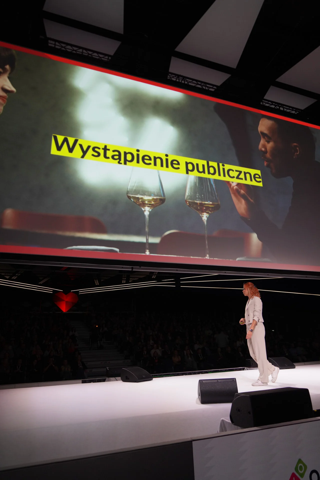 Kama Kotowska podczas wystąpienia na dużej scenie konferencyjnej, na ekranie hasło „Wystąpienie publiczne”